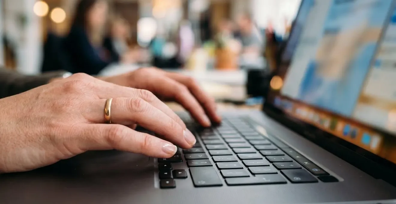 Close-up of hands using project management software on laptop to track research and development team activities